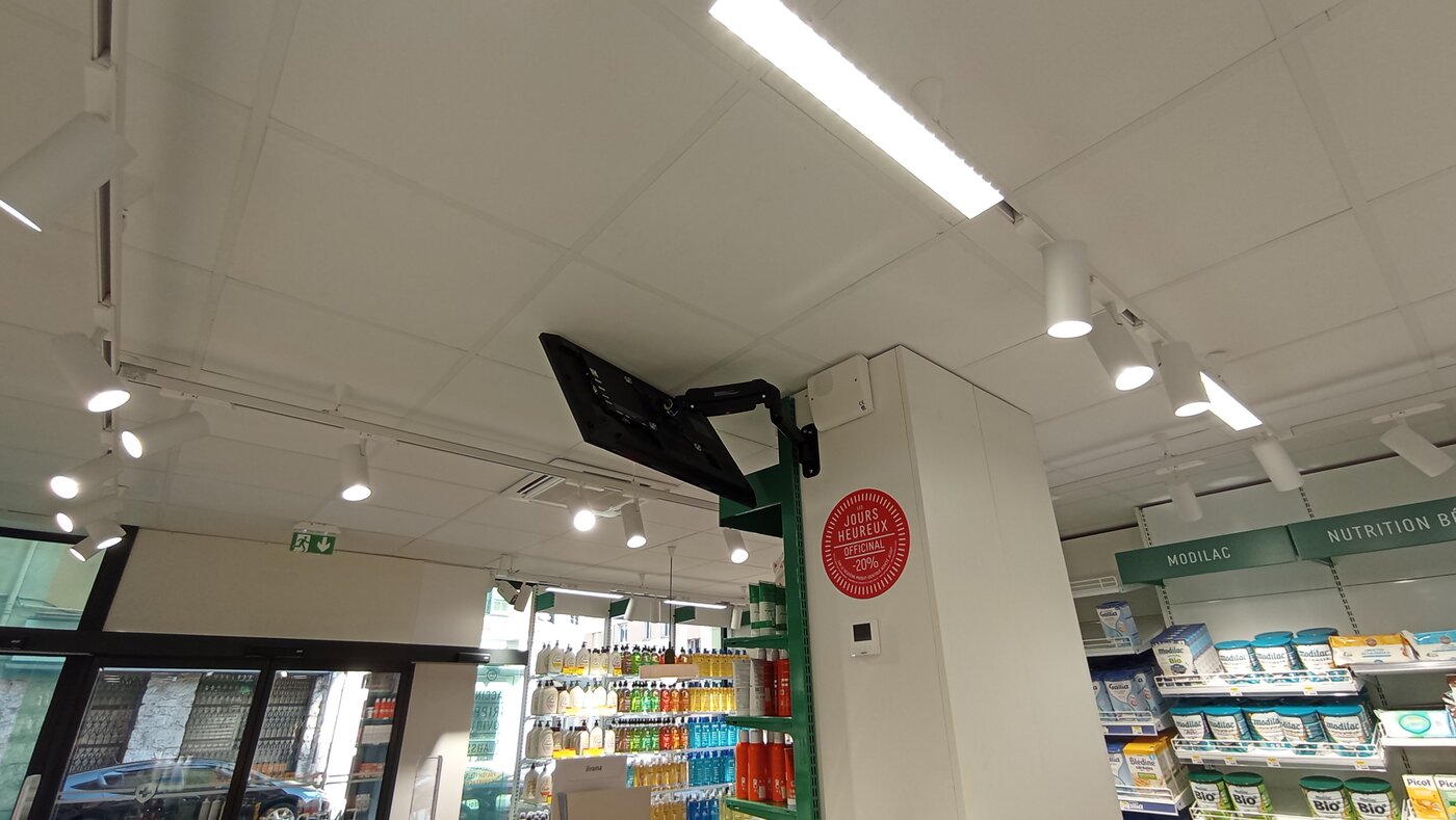 Écran fixé sur bras articulé sur un pilier de la pharmacie