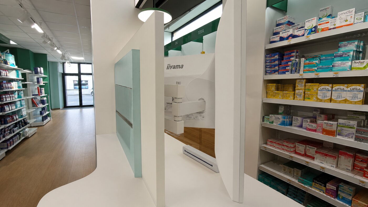 Écran iiyama fixé sur bras articulé dans l'espace de conseil de la pharmacie